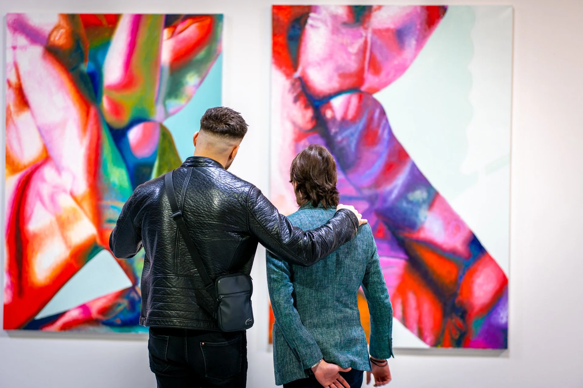 Deux personnes regardant des peintures abstraites dans une galerie d'art.