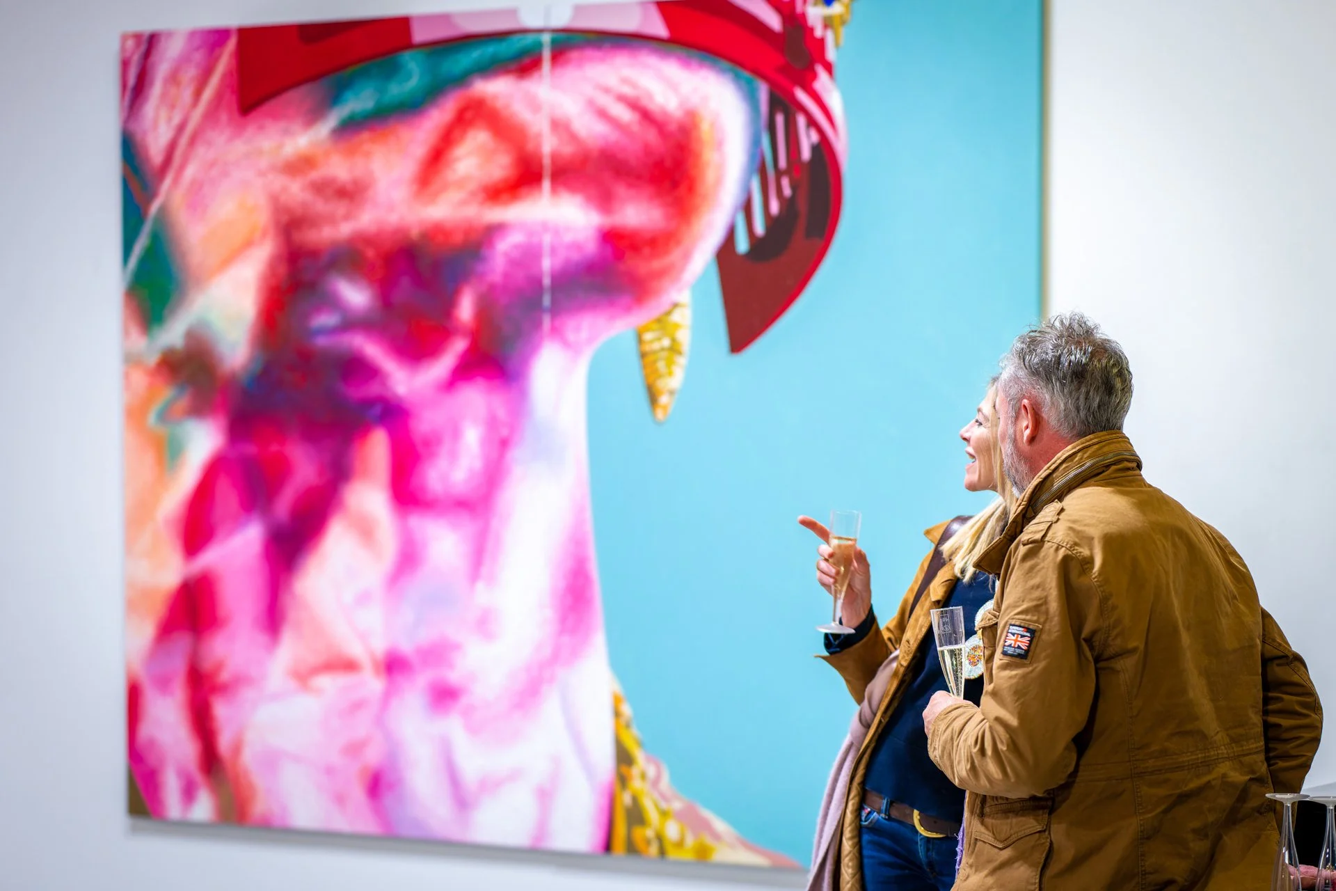 Deux personnes admirent une peinture abstraite aux couleurs vives dans une galerie d'art.