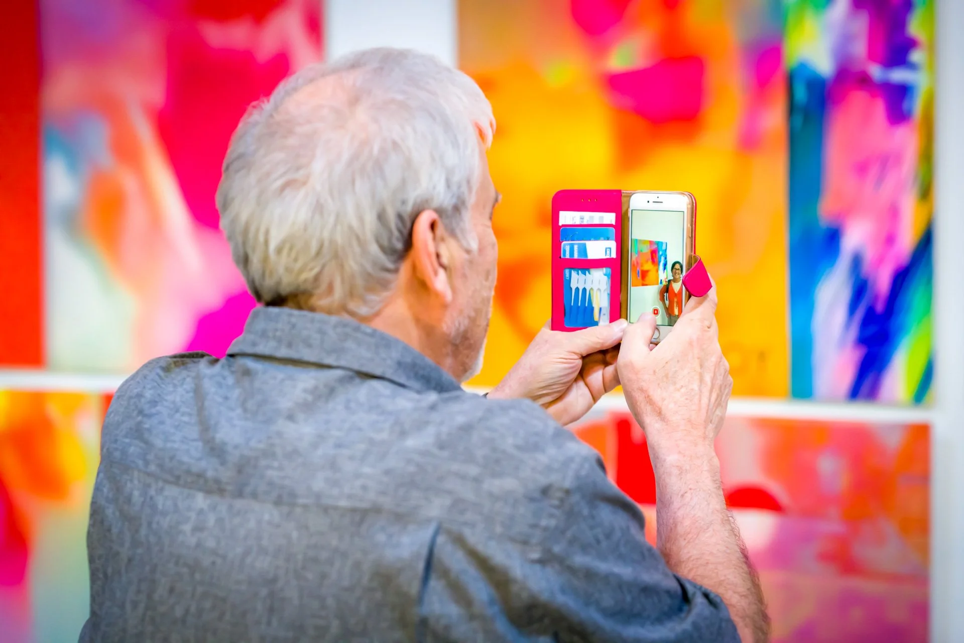 photo graphie professionnelle d'une personne dans une galerie d'art prenant un photo avec son téléphone d'une personne devant un tableau. Cette image a été immortalisée par une photographe pro de ISOWAY et montre des tons très colorés et saturés.