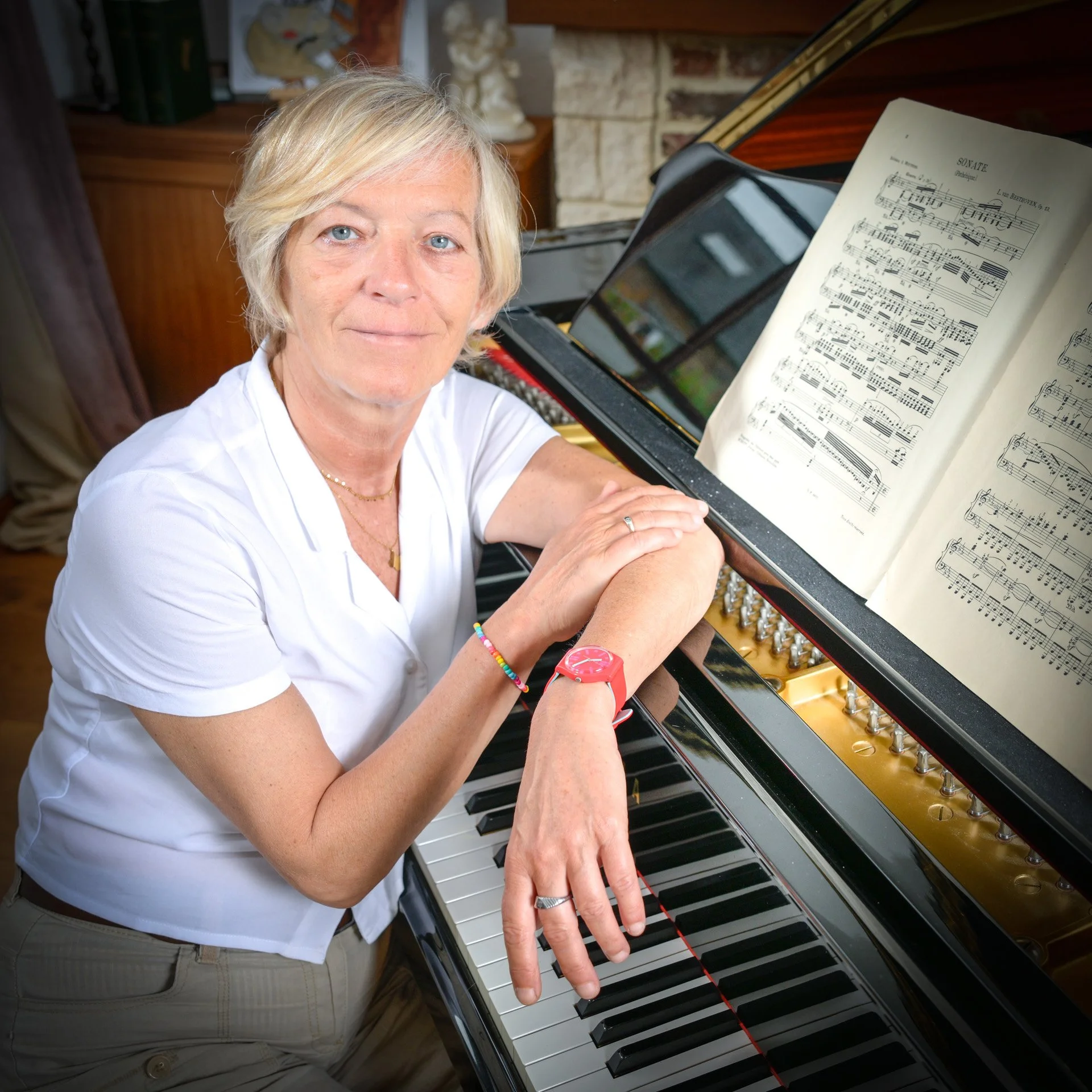 A person sitting next to a piano, with sheet music lying on top of it.