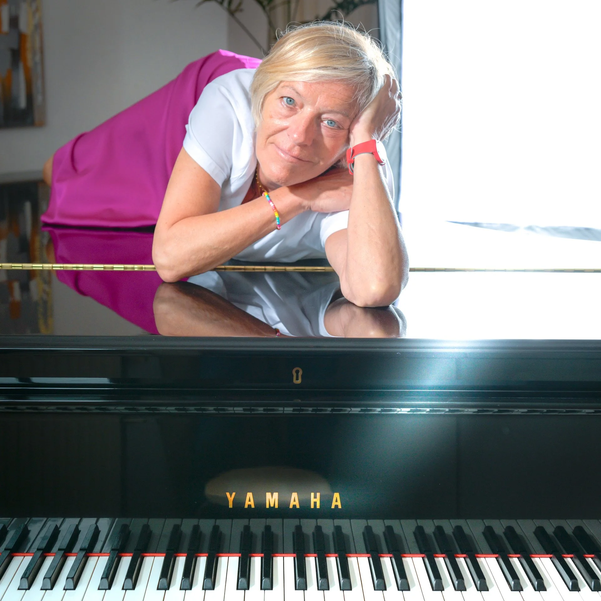 Fabienne Vignier s’appuie sur son piano à queue, la tête posée sur ses mains, au-dessus du clavier.