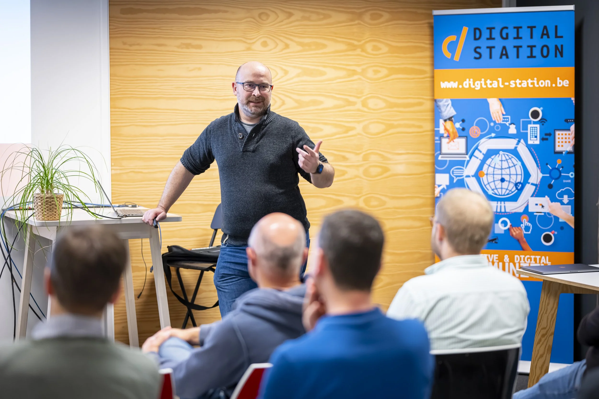 Denys Bornauw s’adresse à un public assis, près d’une bannière Digital Station, lors du meetup WalChain à Charleroi.