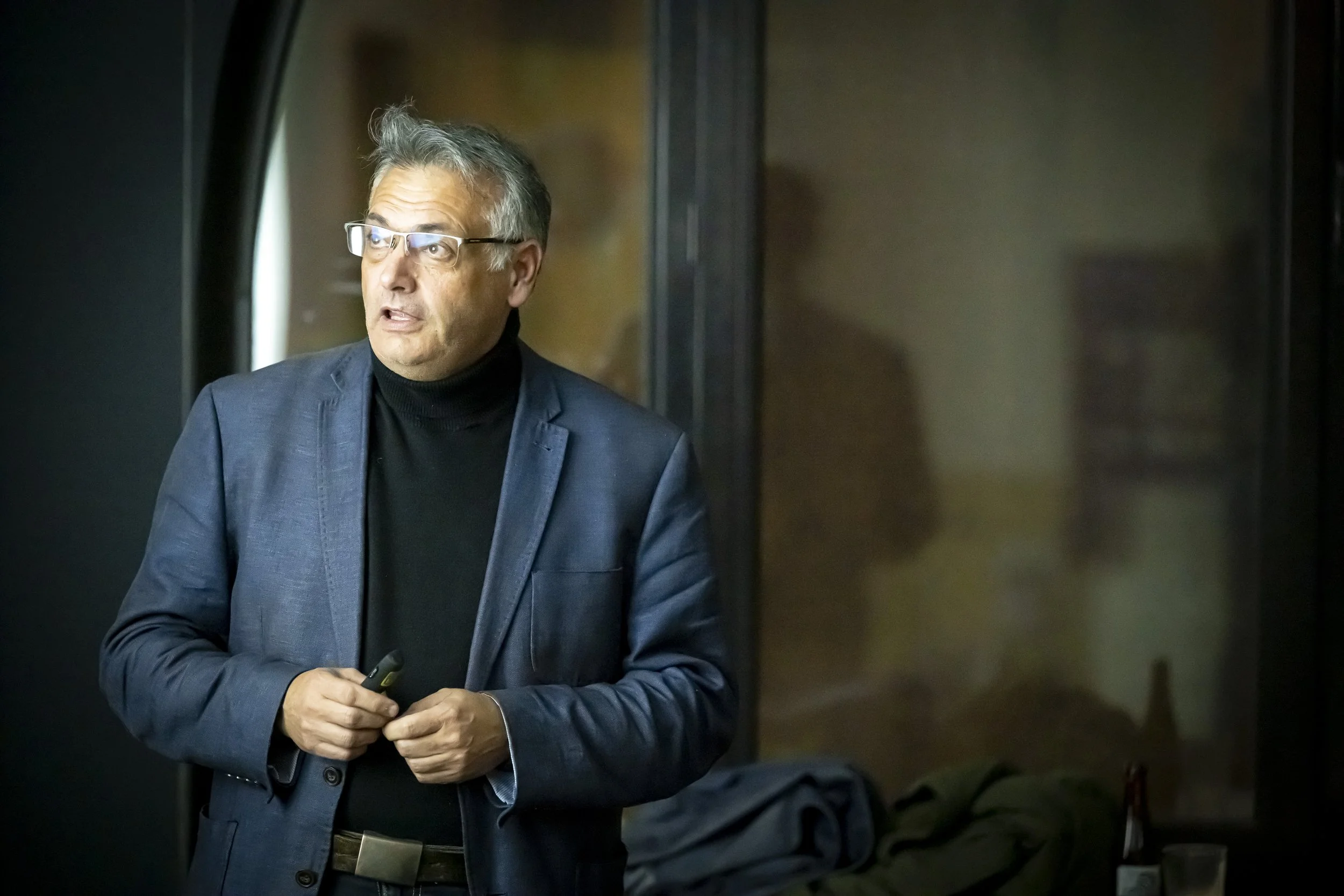Vincent Parissis, en veste bleue et col roulé noir, intervient lors du meetup WalChain à Charleroi.