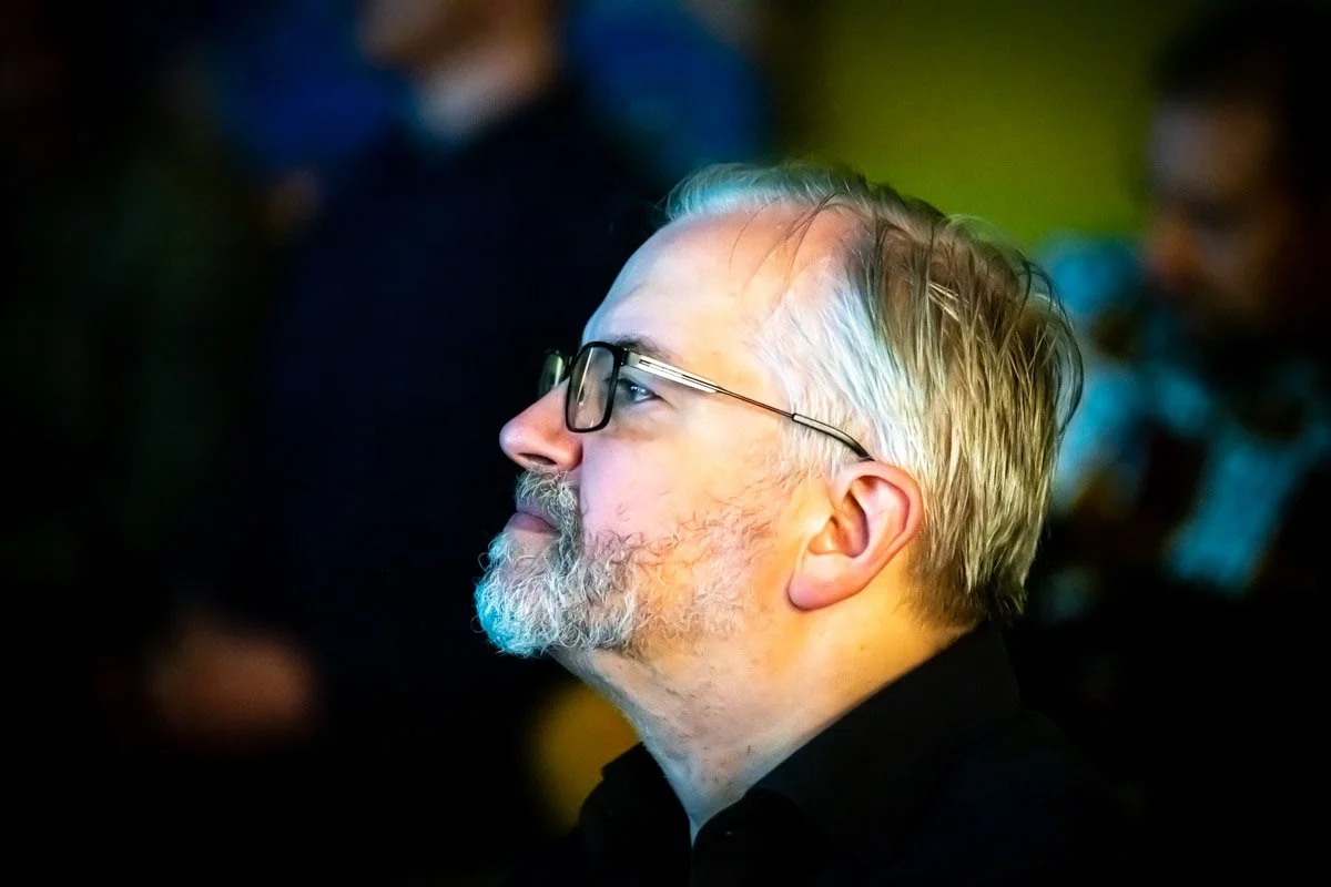 Vincent Callebaut, vu de profil avec des lunettes et une barbe grise, lors du meetup WalChain à Charleroi.