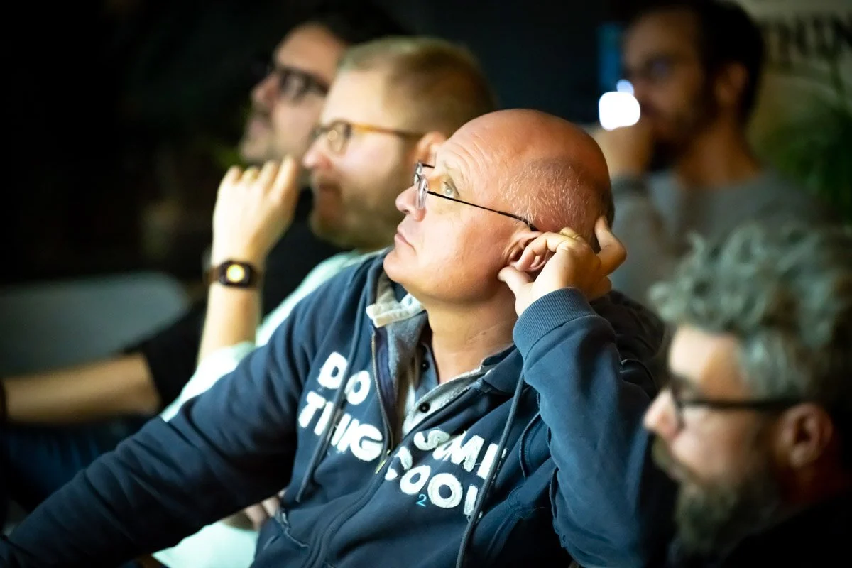 Bruno Lambotte et d’autres participants assis écoutent une présentation lors du meetup WalChain à Charleroi.