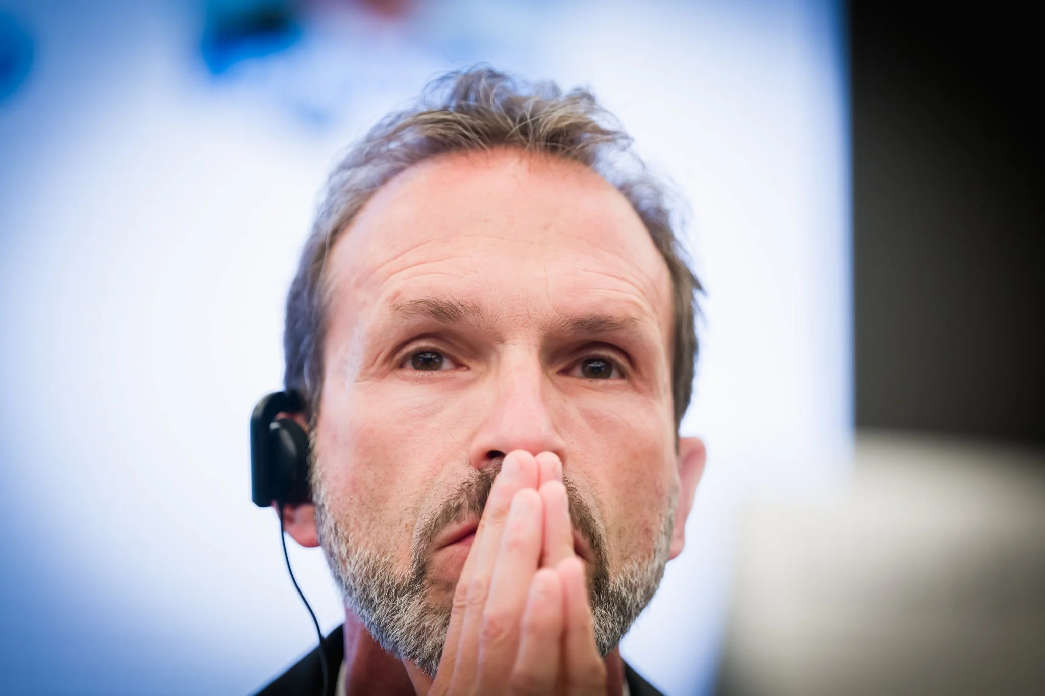 Photo professionnelle d'un homme pensif avec un casque audio, photographié pendant une conférence dans le quartier européen à Bruxelles.