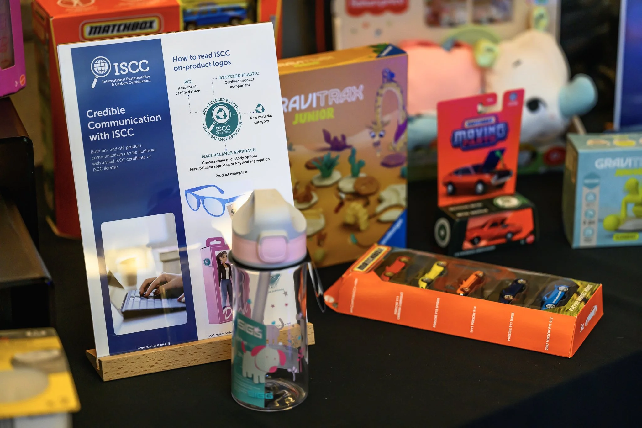 A reusable bottle and packaged products sit in front of an ISCC information board.