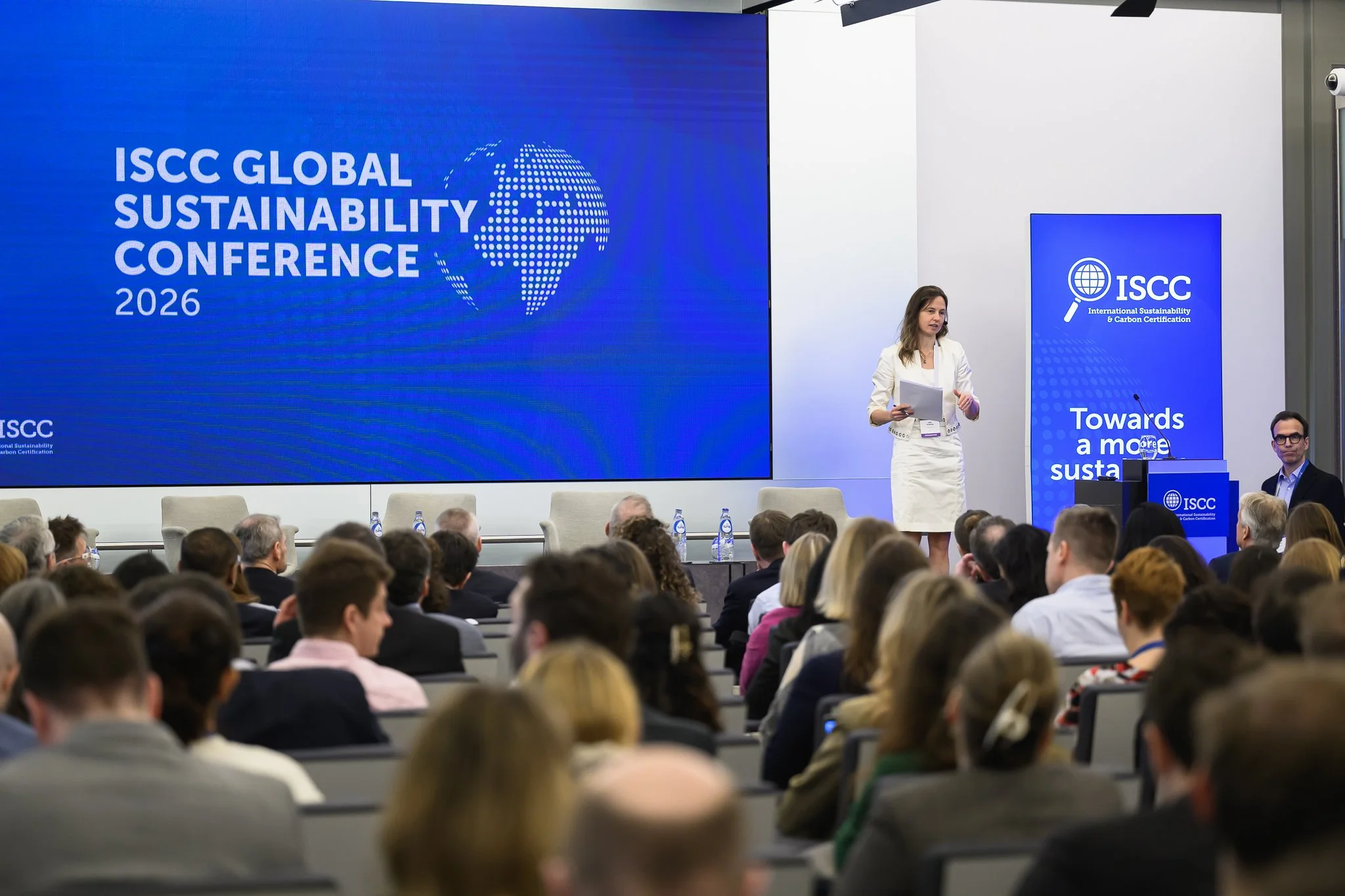 A woman stands on stage beneath the ISCC Global Sustainability Conference 2026 screen.