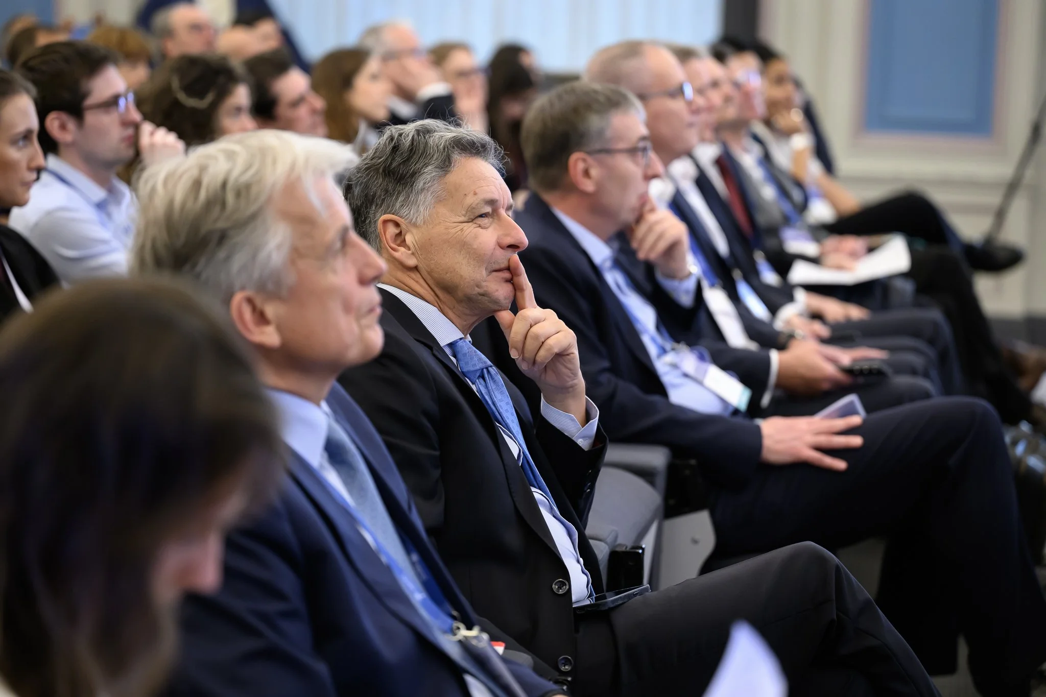 Conference participants sit in rows and listen to a presentation.