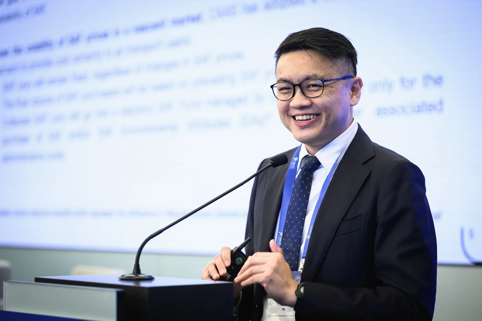 A man in glasses smiles while presenting at the lectern.