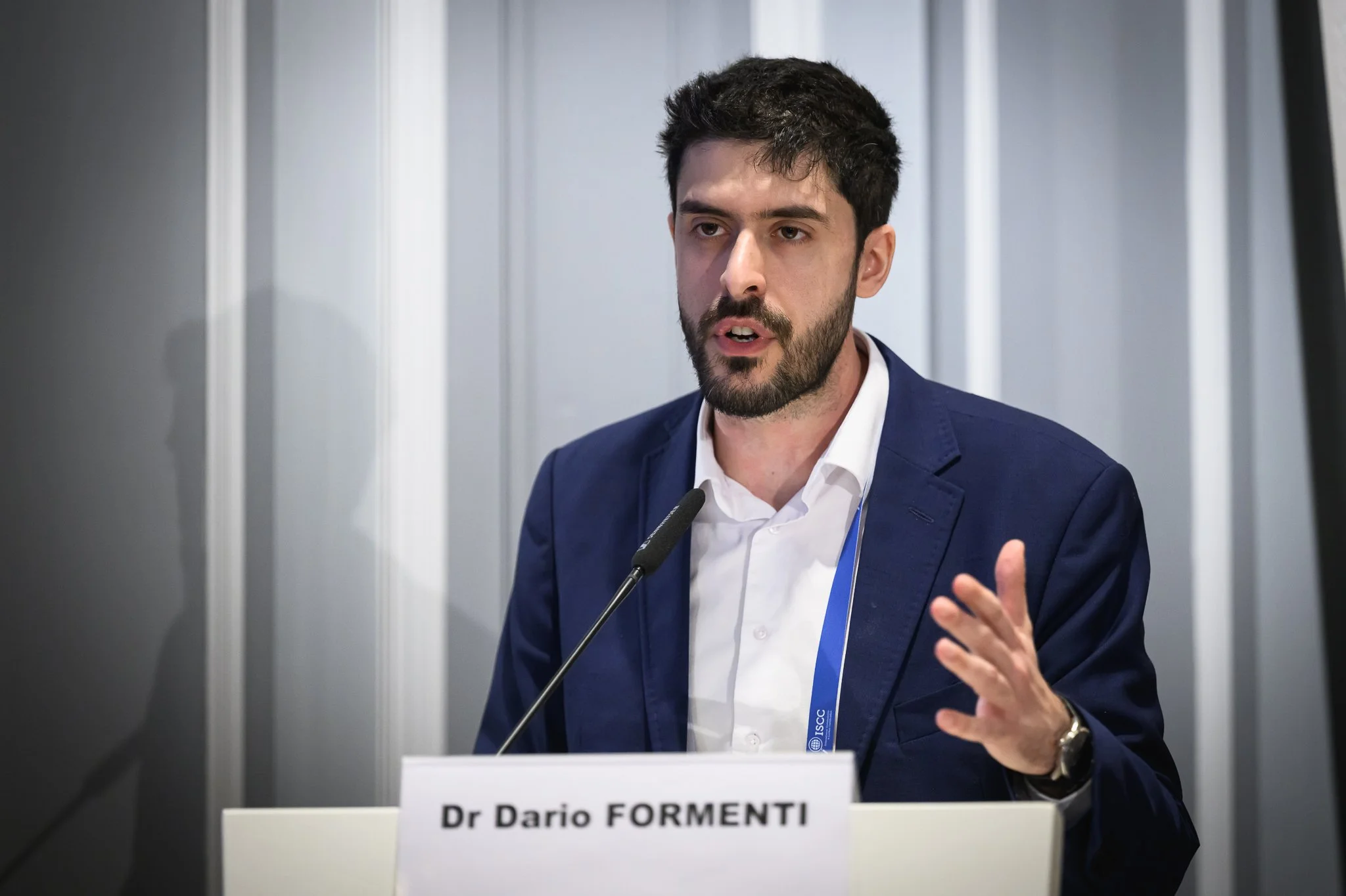 Dr Dario Formenti gestures while speaking at the lectern.