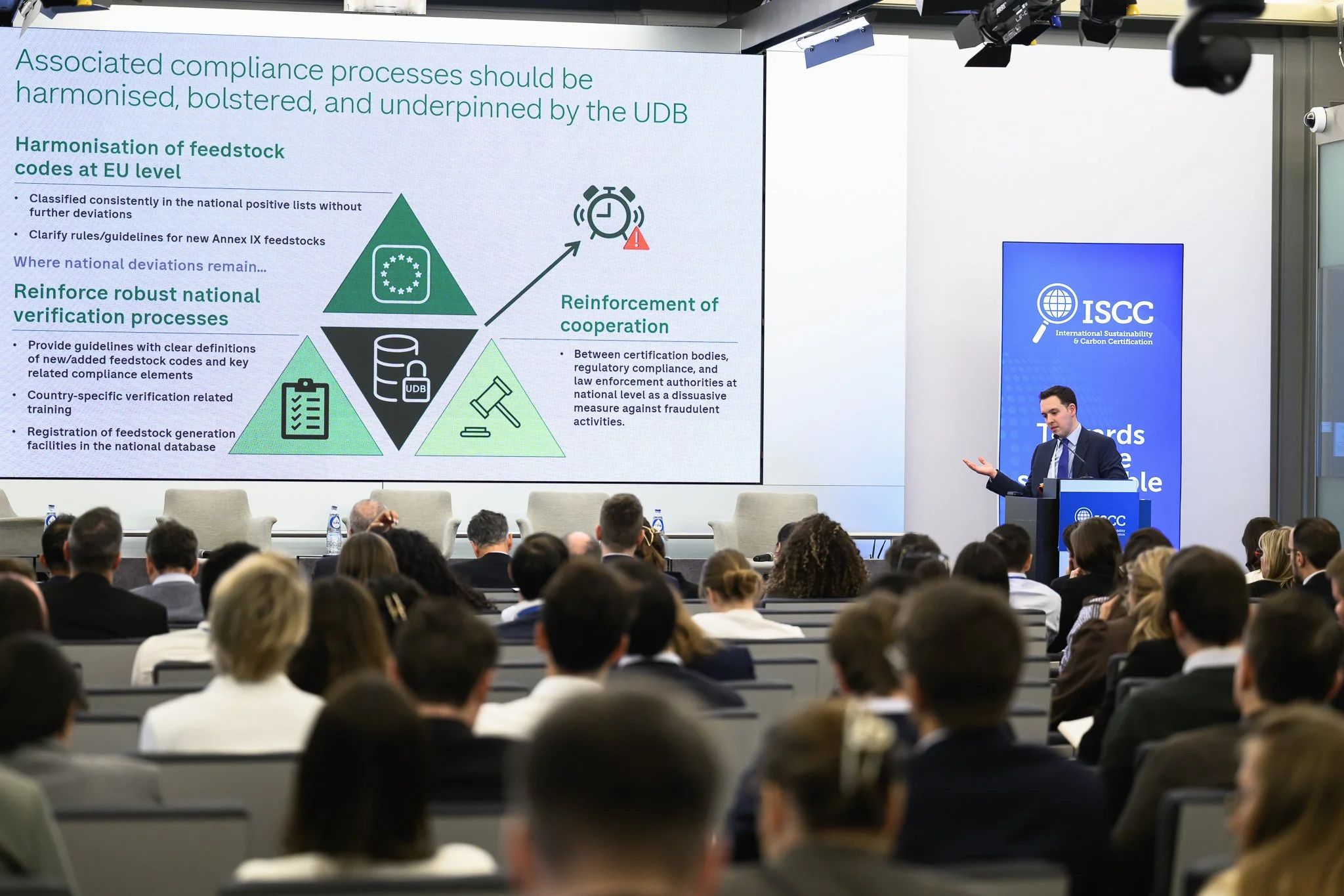 The audience watches a presentation slide with a green triangular diagram.