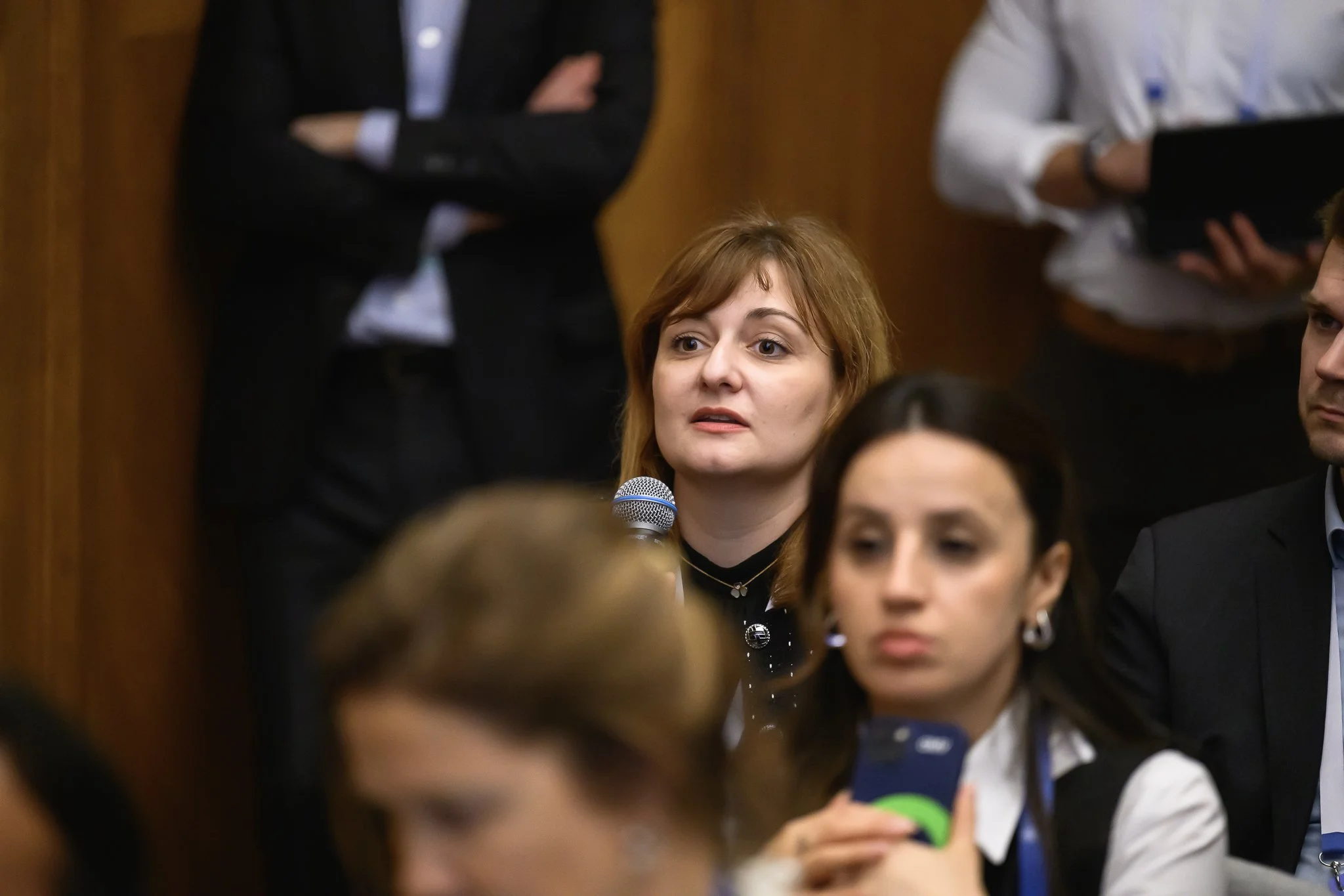 Two seated women look towards the speaker during a conference session.