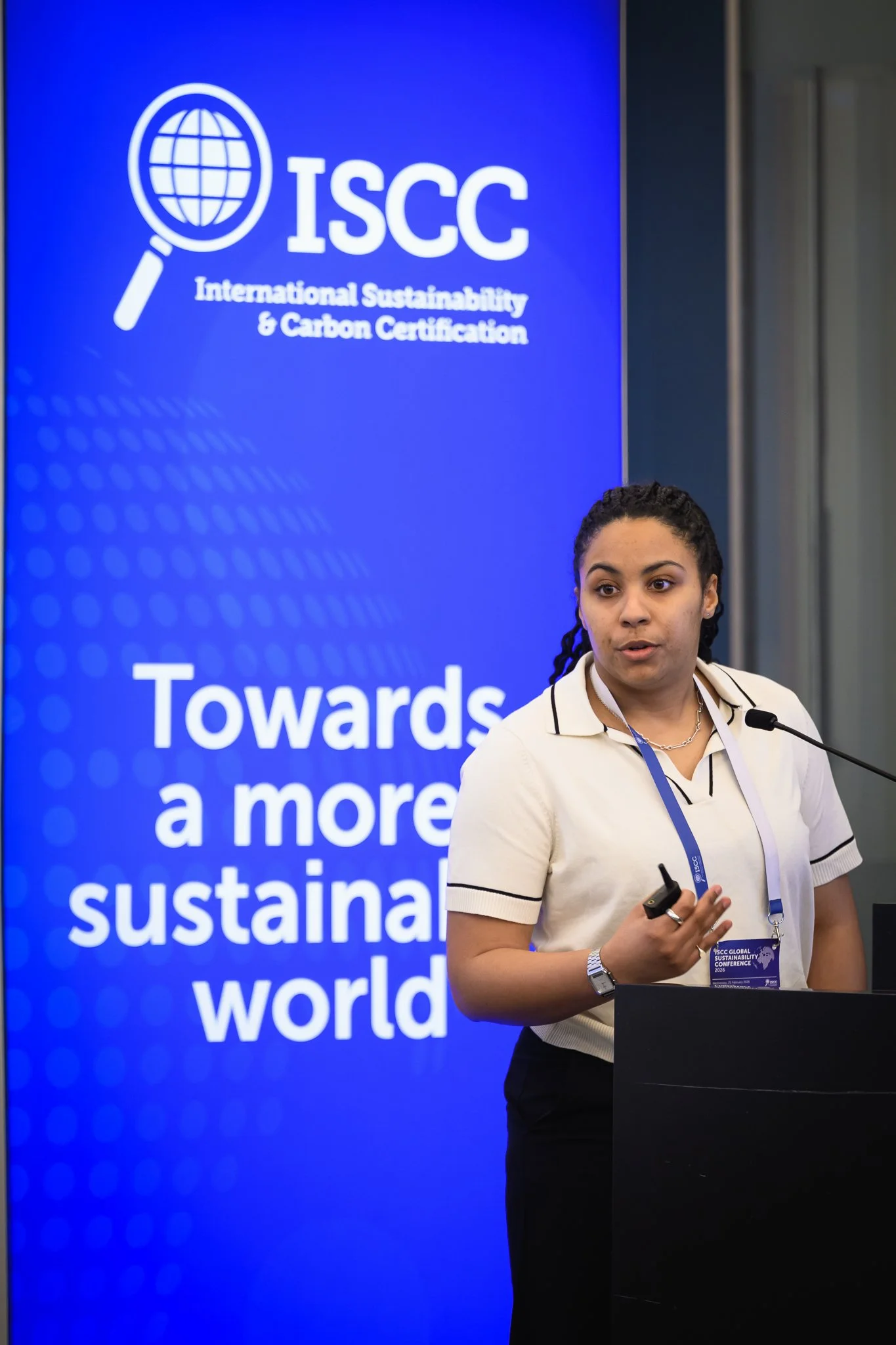 A woman addresses the audience from a lectern beside an ISCC banner.