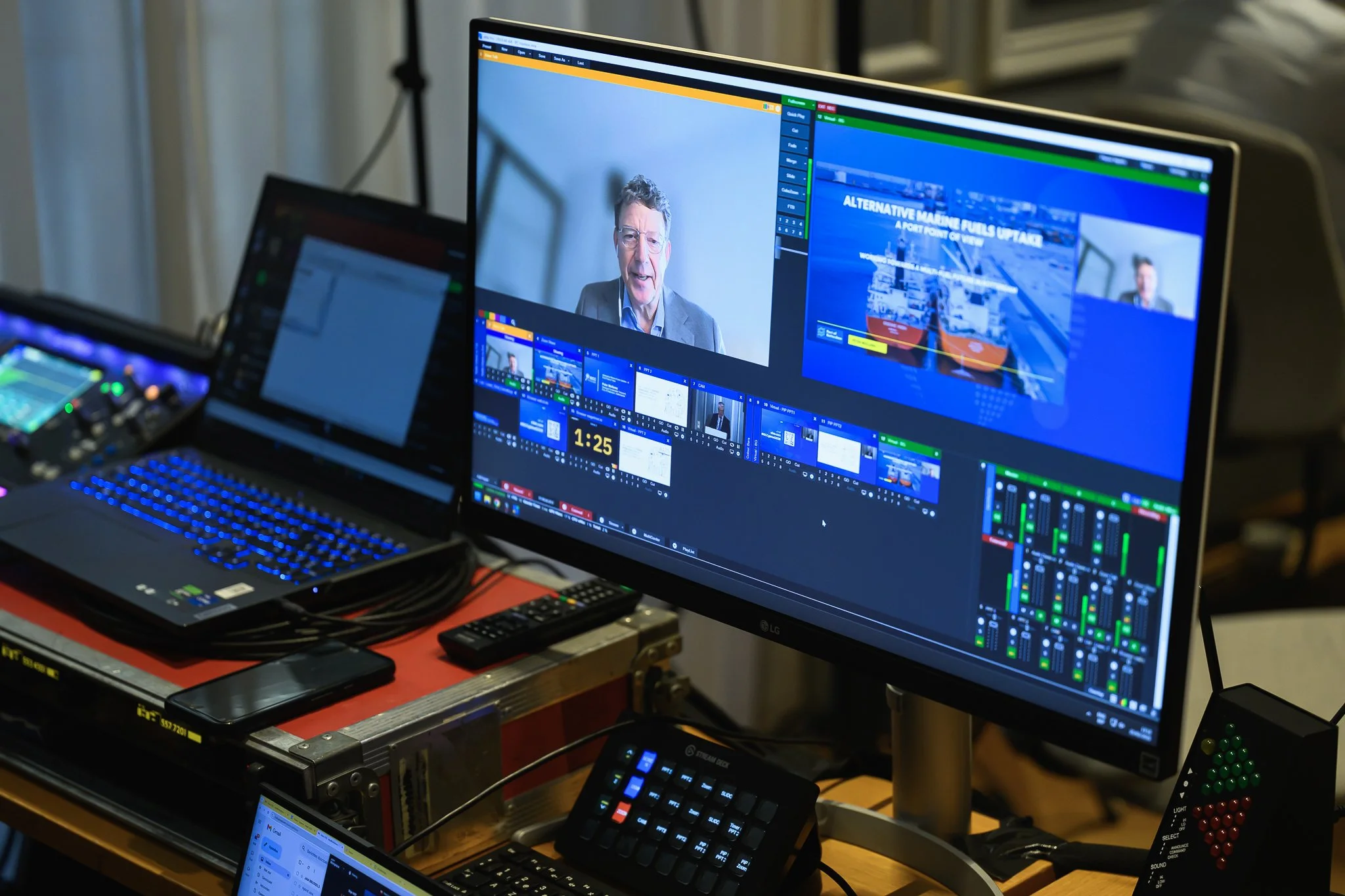 Close-up of video production monitors, a laptop and control equipment displaying the conference broadcast.