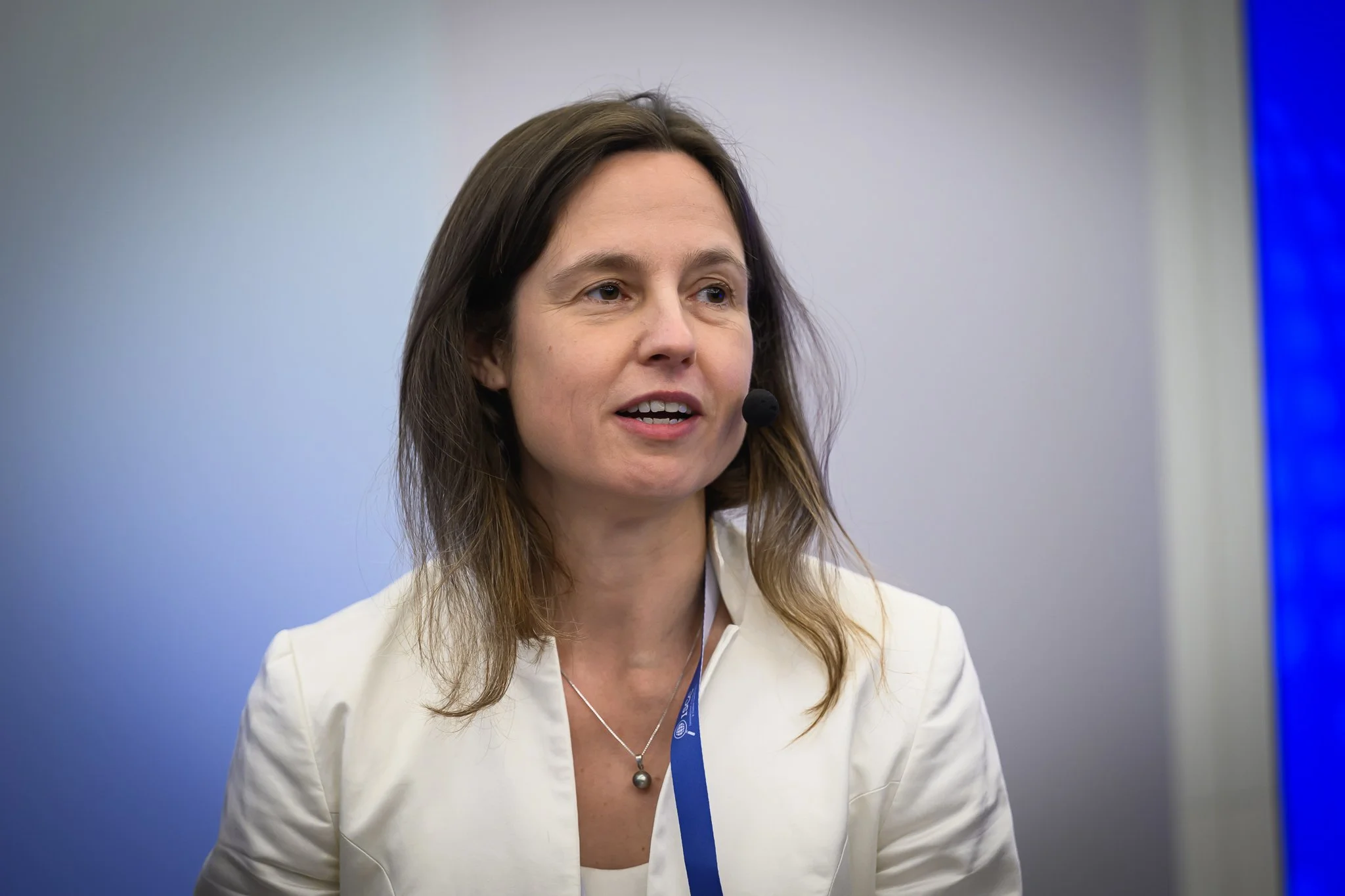 A woman in a white jacket listens during the panel discussion.
