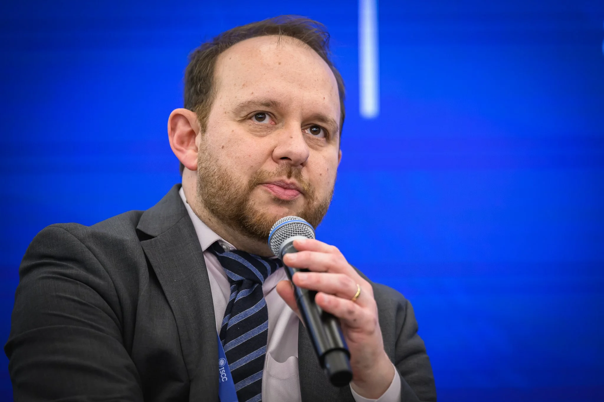 Close-up of a man in a striped tie speaking into a microphone.