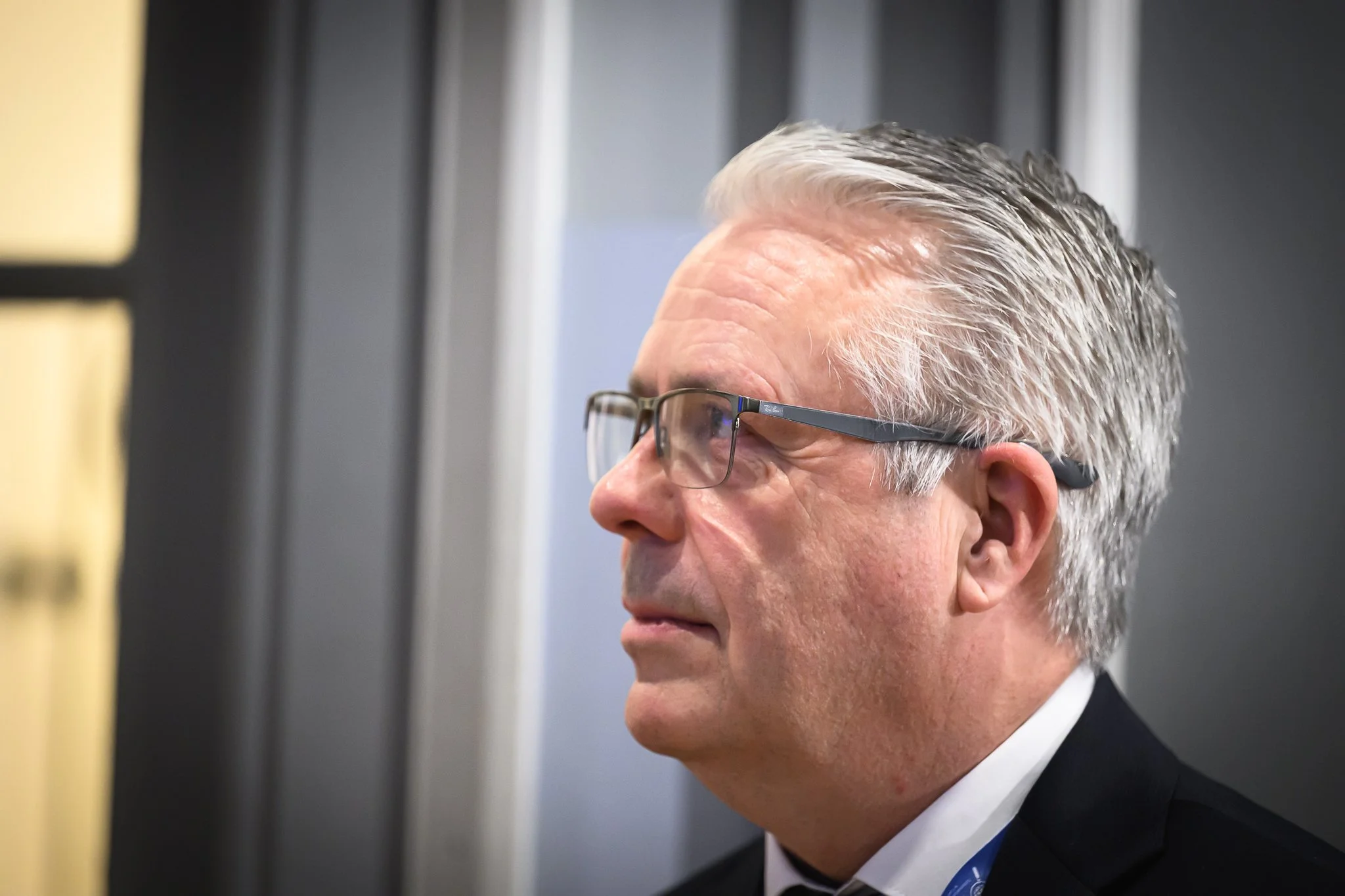 Close-up profile of an older man with glasses listening during a session.
