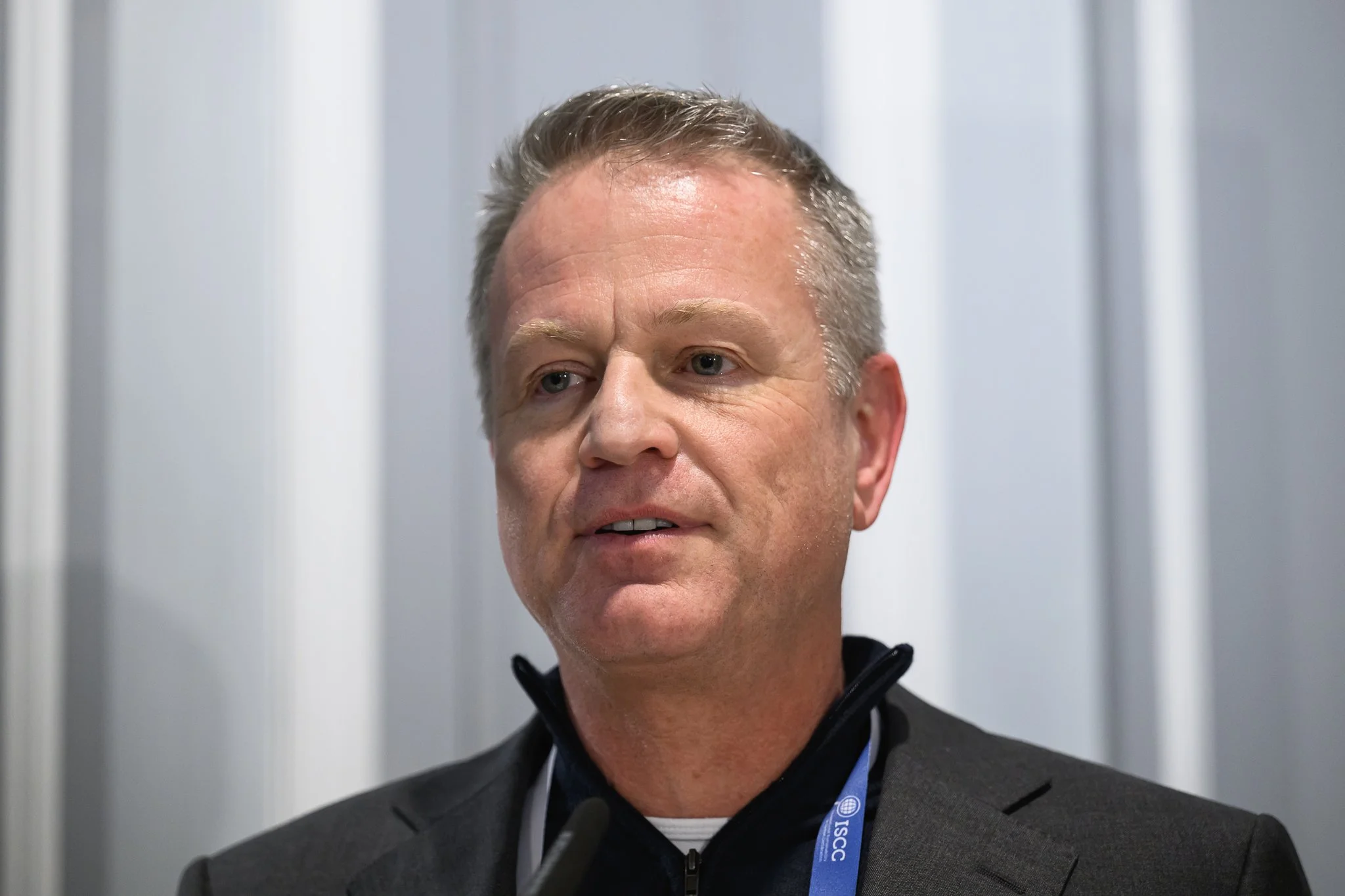 Close-up of a man in a dark jacket addressing the conference.