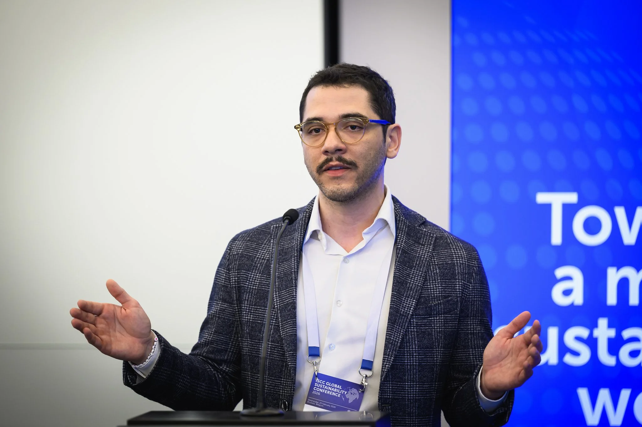 A presenter spreads his hands apart while addressing the audience.