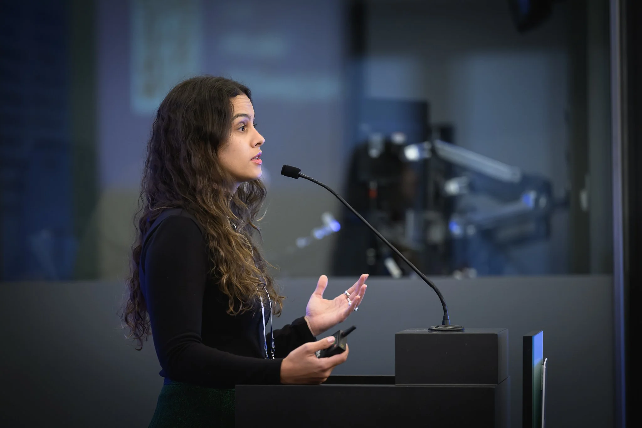Side view of a woman with curly hair presenting at the lectern.