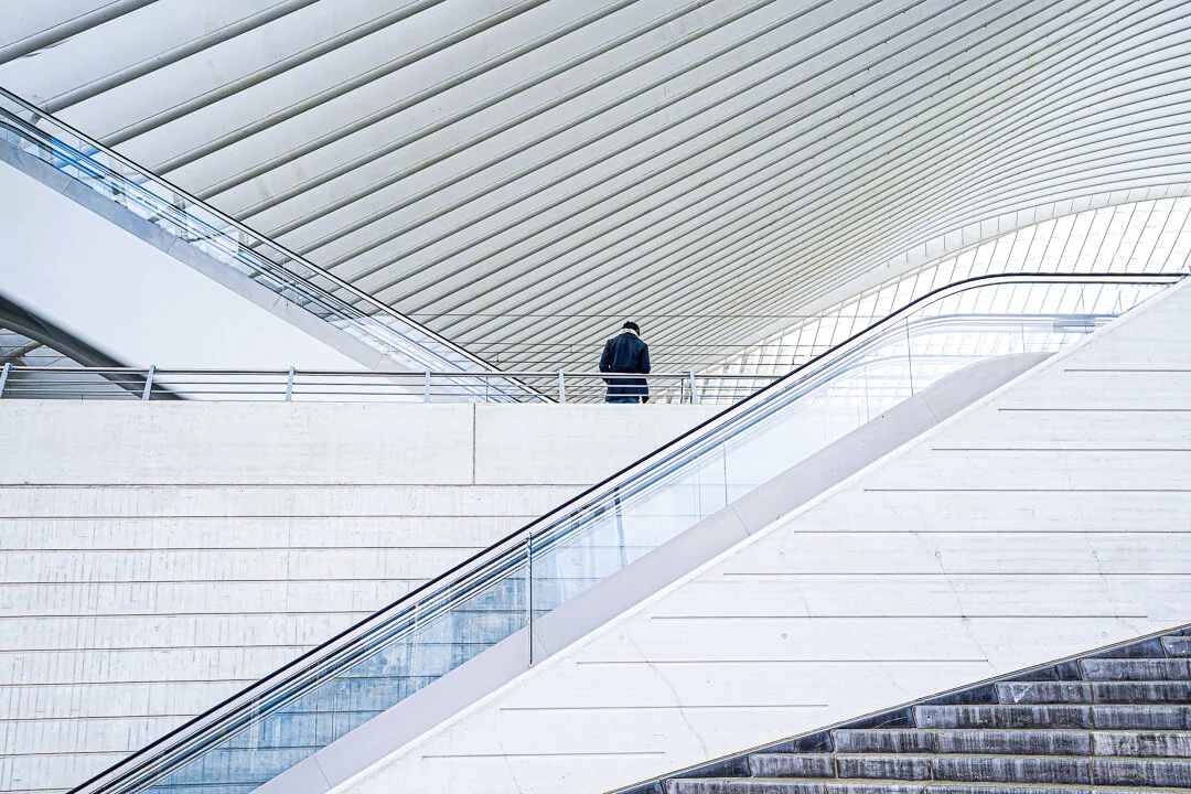 Les escaliers et passerelles de la gare de Liège-Guillemins sous sa grande toiture blanche aux lignes courbes.