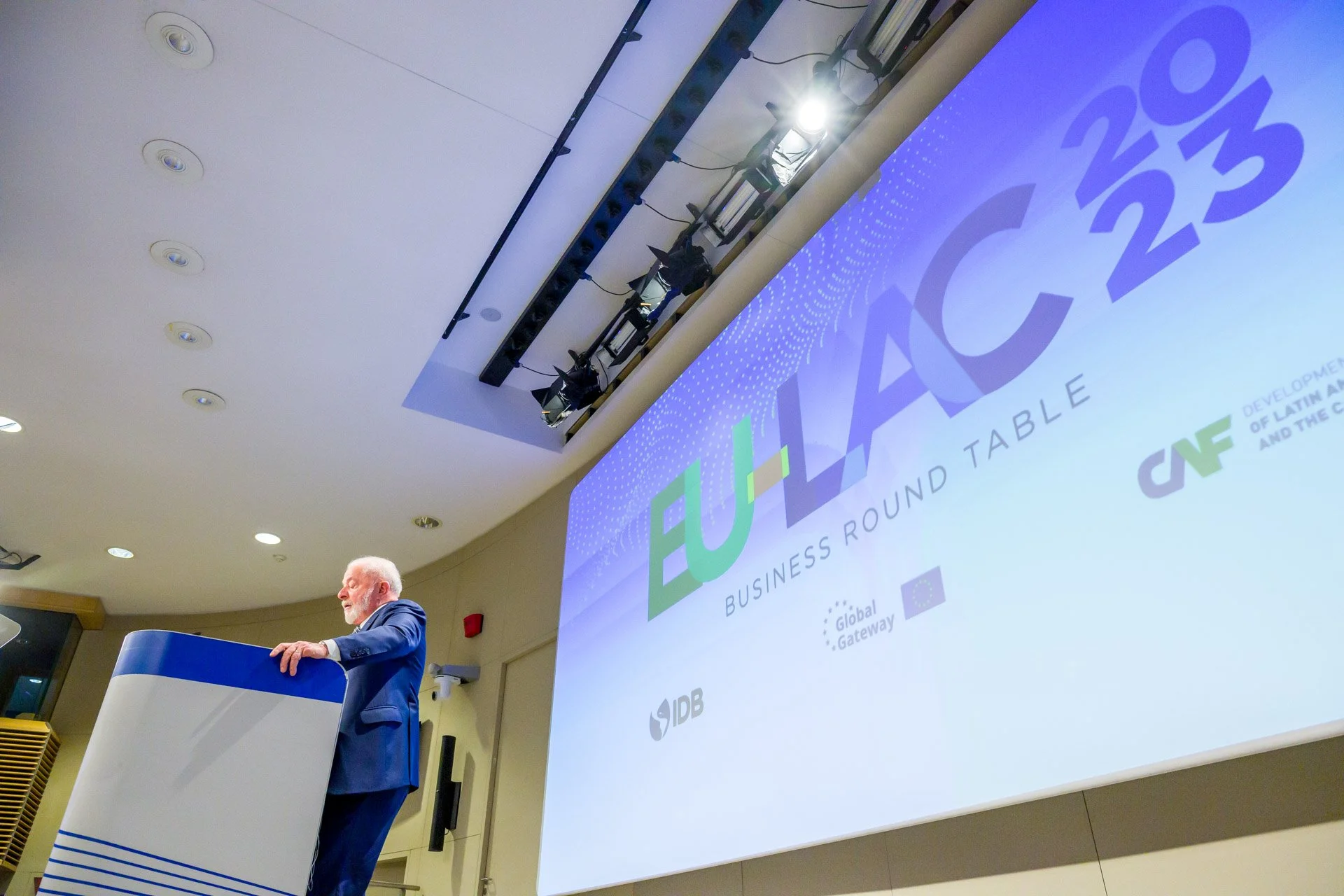 Une personne parlant lors d'une conférence sur une scène avec un grand écran affichant le texte "EU-ACC 2023" et le sous-titre "Business Round Table".