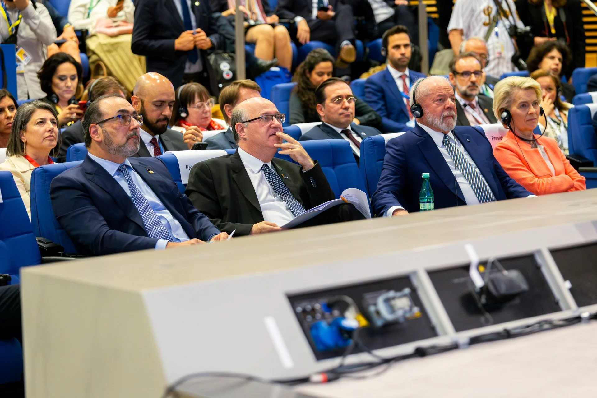 Personnes lors d'une conférence, portant des écouteurs, assises dans un auditorium.