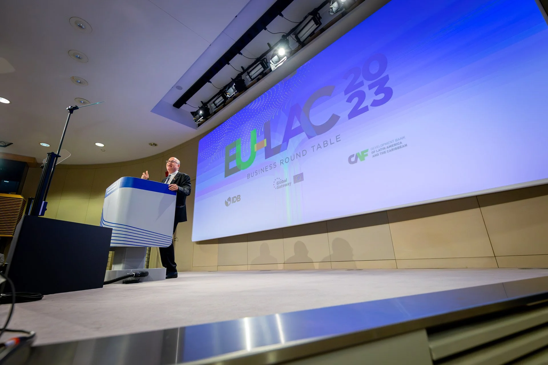 Conférence EU-LAC 2023, orateur au podium, écran affichant des logos d'organisations.
