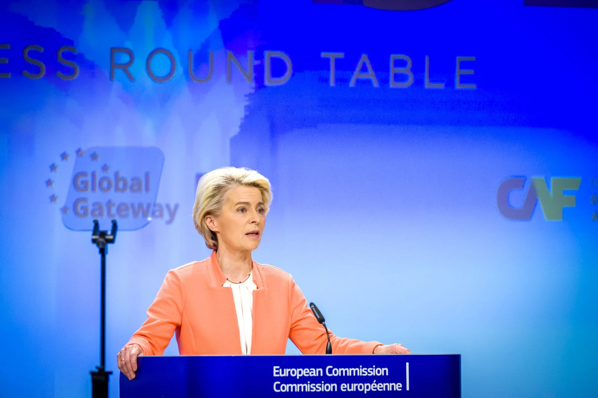 Personne parlant lors de l'événement "Global Gateway" à la Commission européenne avec un fond bleu.