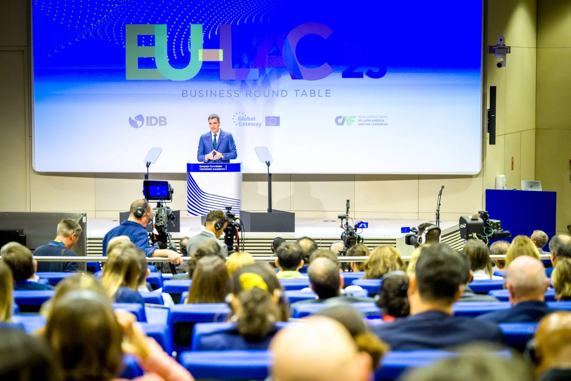 Réunion EU-LAC 2023 avec un orateur sur scène, public assis, caméras professionnelles.