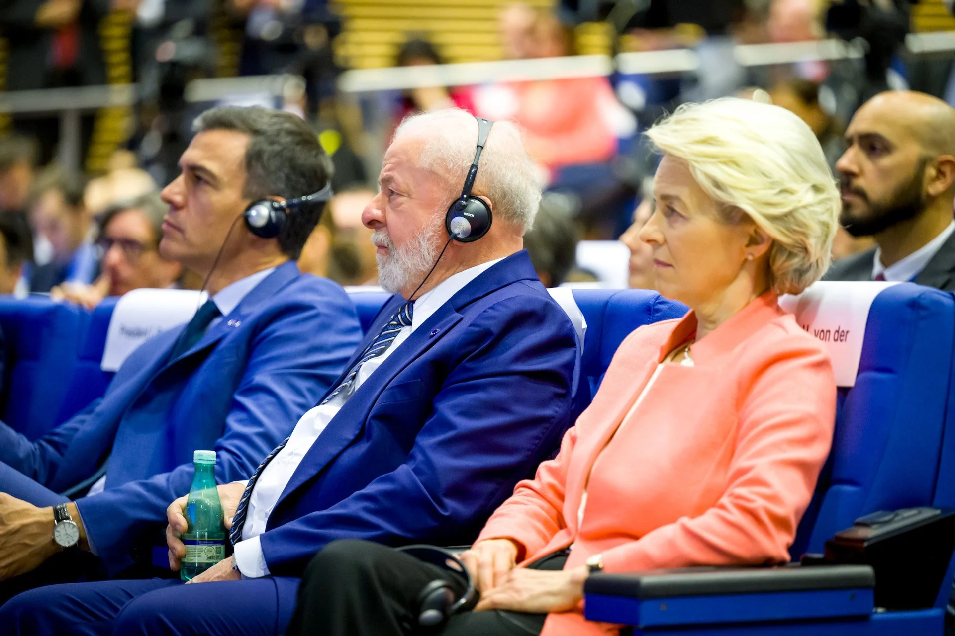 Des personnes assises en costume lors d'une conférence, portant des casques audio.