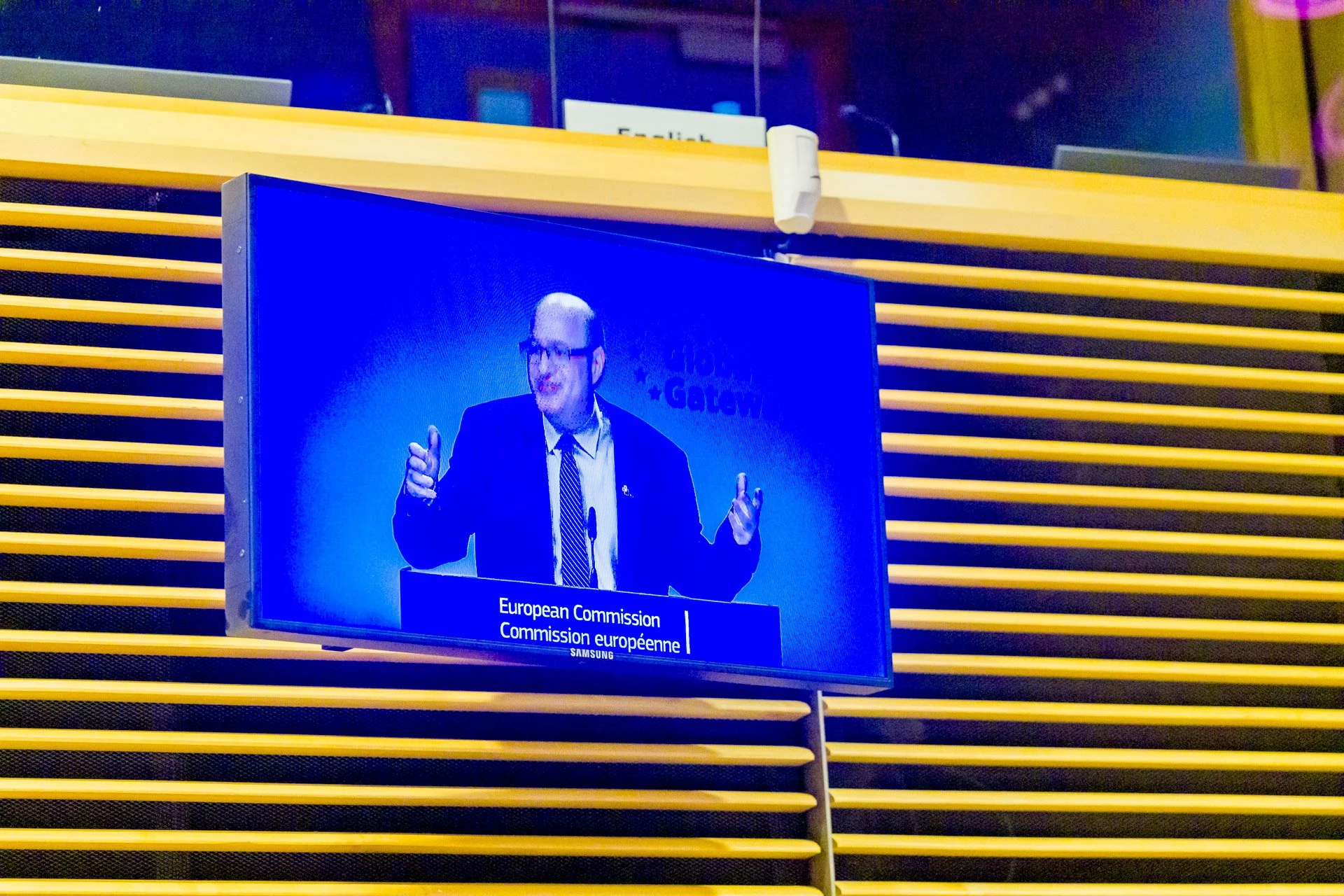 Écran affichant un orateur lors d'une conférence à la Commission européenne.