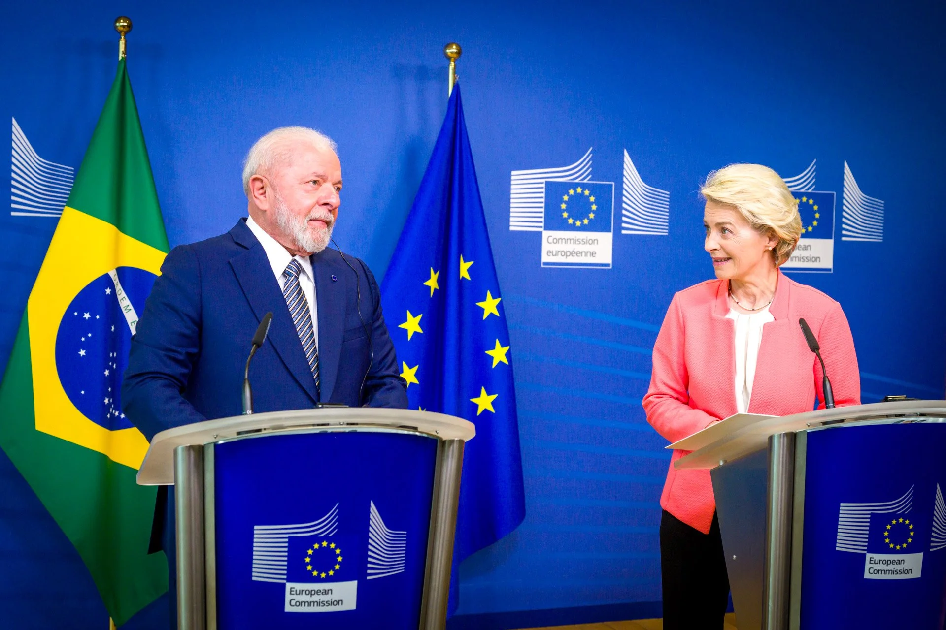 Deux personnes lors d'une conférence de presse avec les drapeaux du Brésil et de l'Union européenne en arrière-plan.