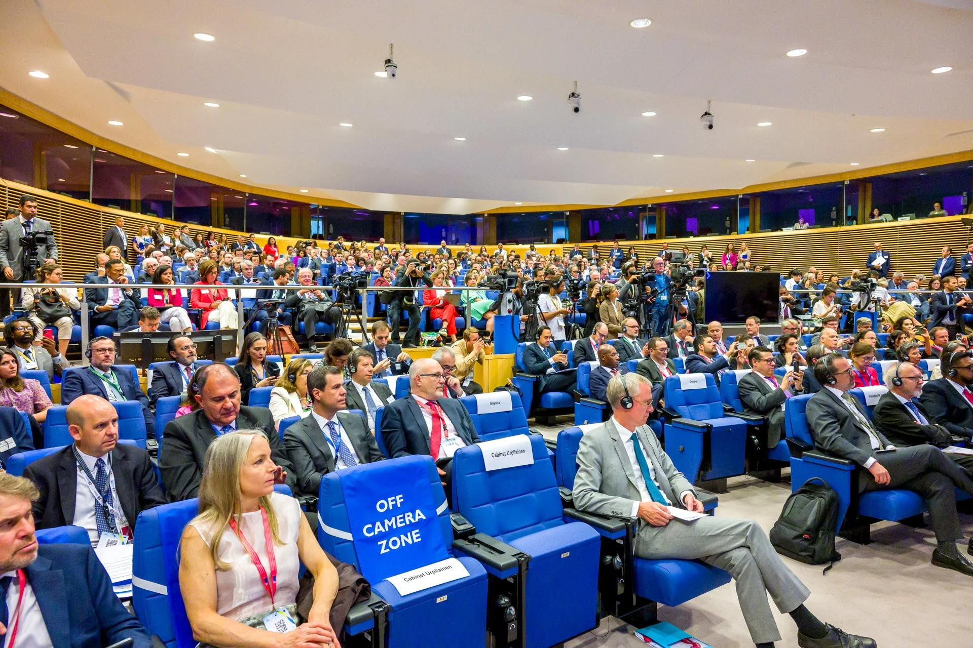 Conférence avec des participants assis dans une salle, certains portant des écouteurs.