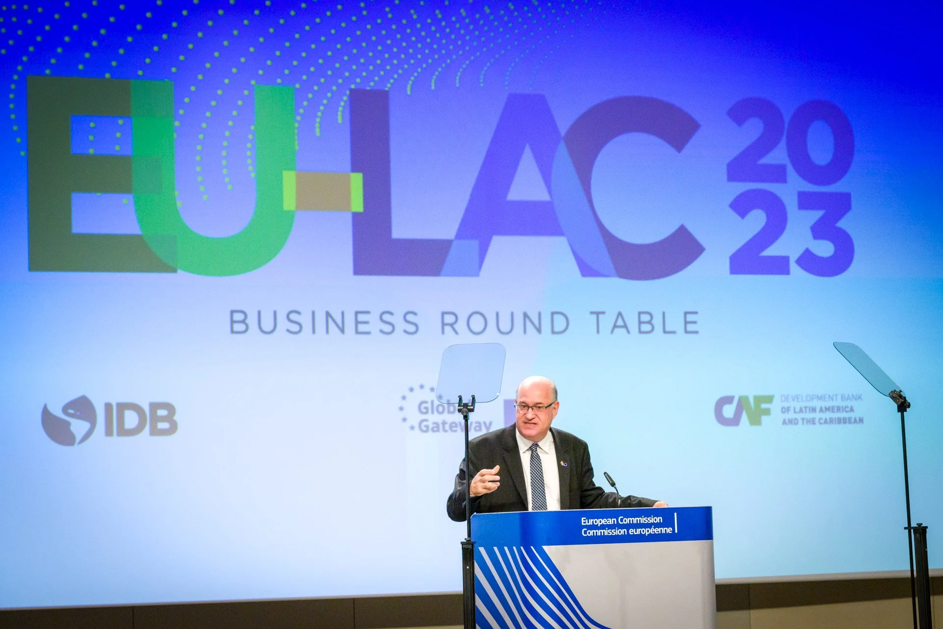 Un conférencier à un podium lors de la table ronde d'affaires EU-LAC 2023, avec des logos d'organisations en arrière-plan.