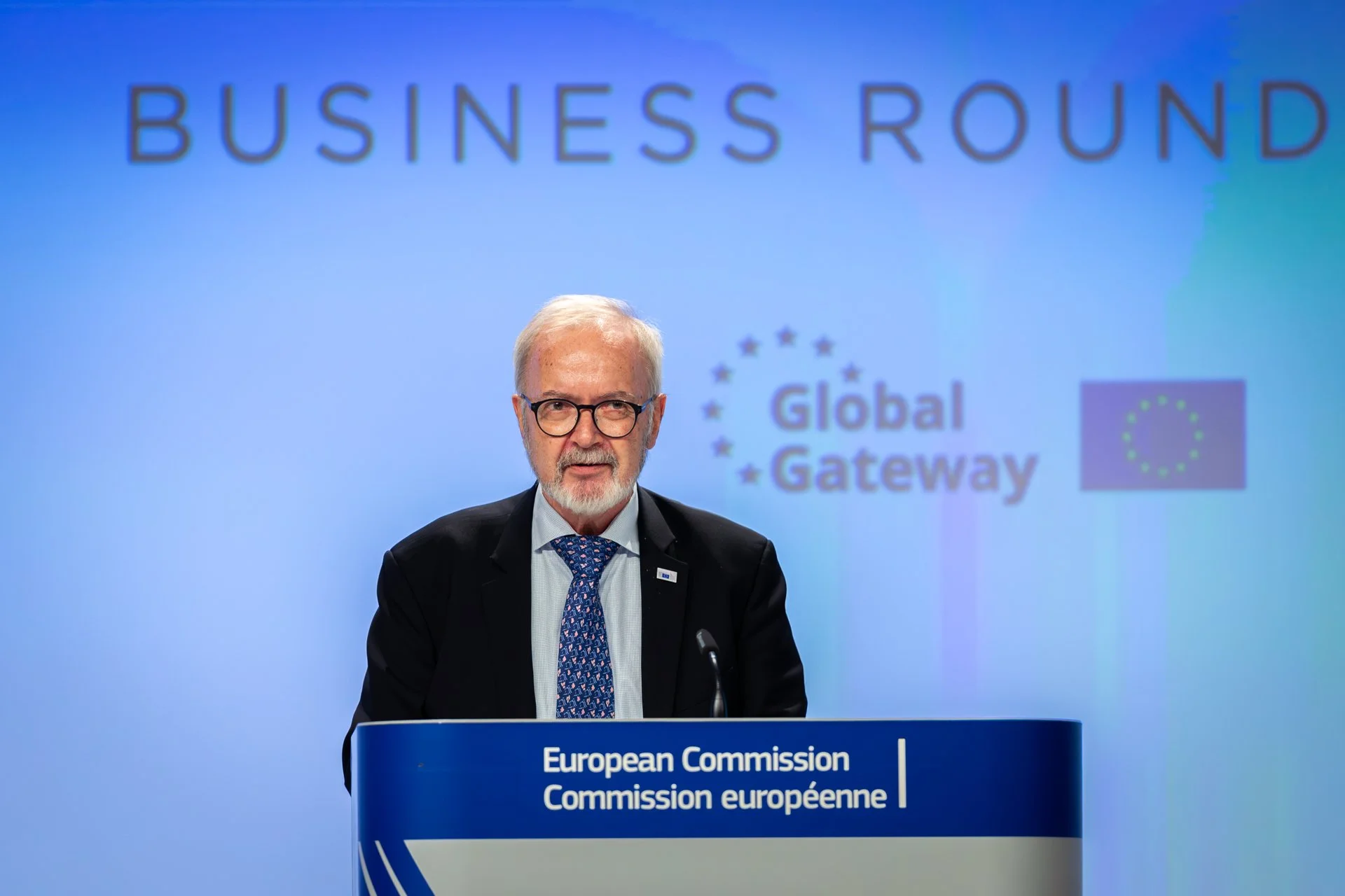 Homme parlant lors d'un événement de la Commission européenne devant un podium, avec "Global Gateway" et drapeau européen en arrière-plan.