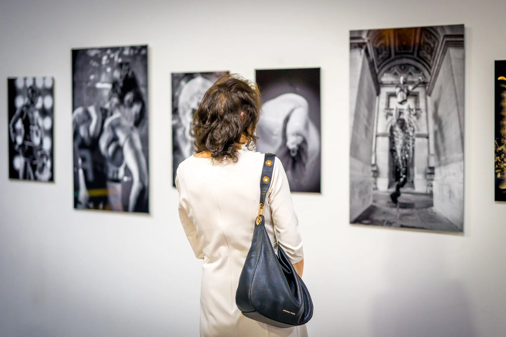 Personne regardant des photographies en noir et blanc dans une galerie.