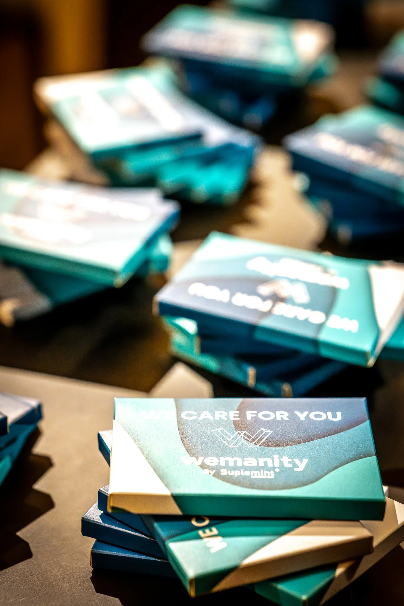 Photographie d'un événement d'entreprise. Boîtes superposées avec le texte 'We care for you, Wemanity by Suplmint'.