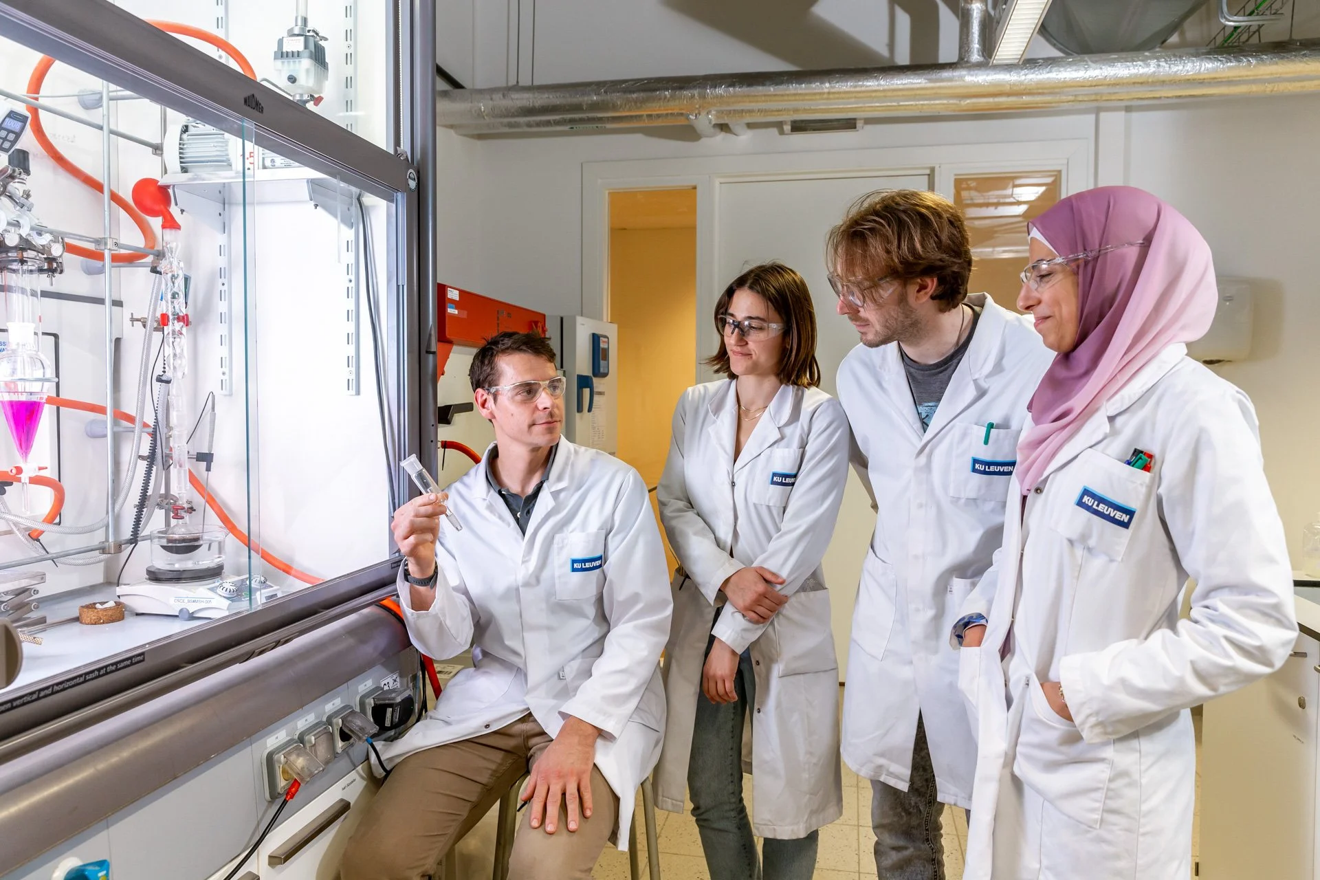Photographie professionnelle d'une équipe de quatre chercheurs dans une laboratoire devant une hotte à flux laminaire prise par un photographe pro de ISOWAY