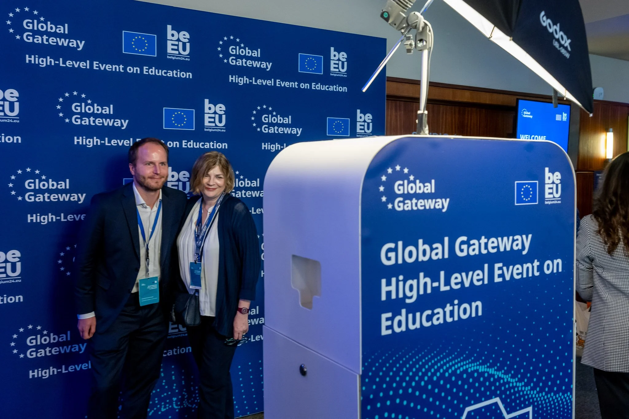 Two people are posing for a photograph at the ‘Global Gateway High-Level Event on Education’, against a blue backdrop featuring the EU logo.