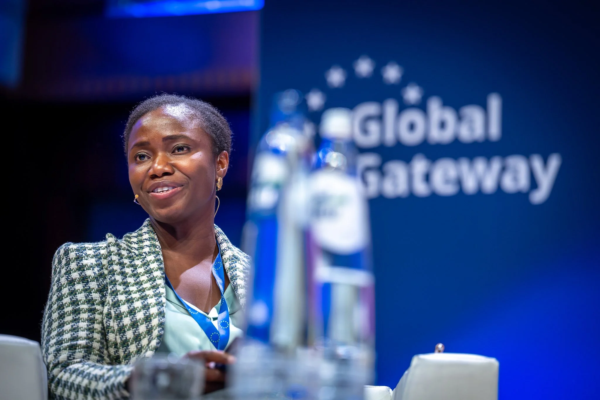 A smiling woman at a conference, with a ‘Global Gateway’ sign in the background.