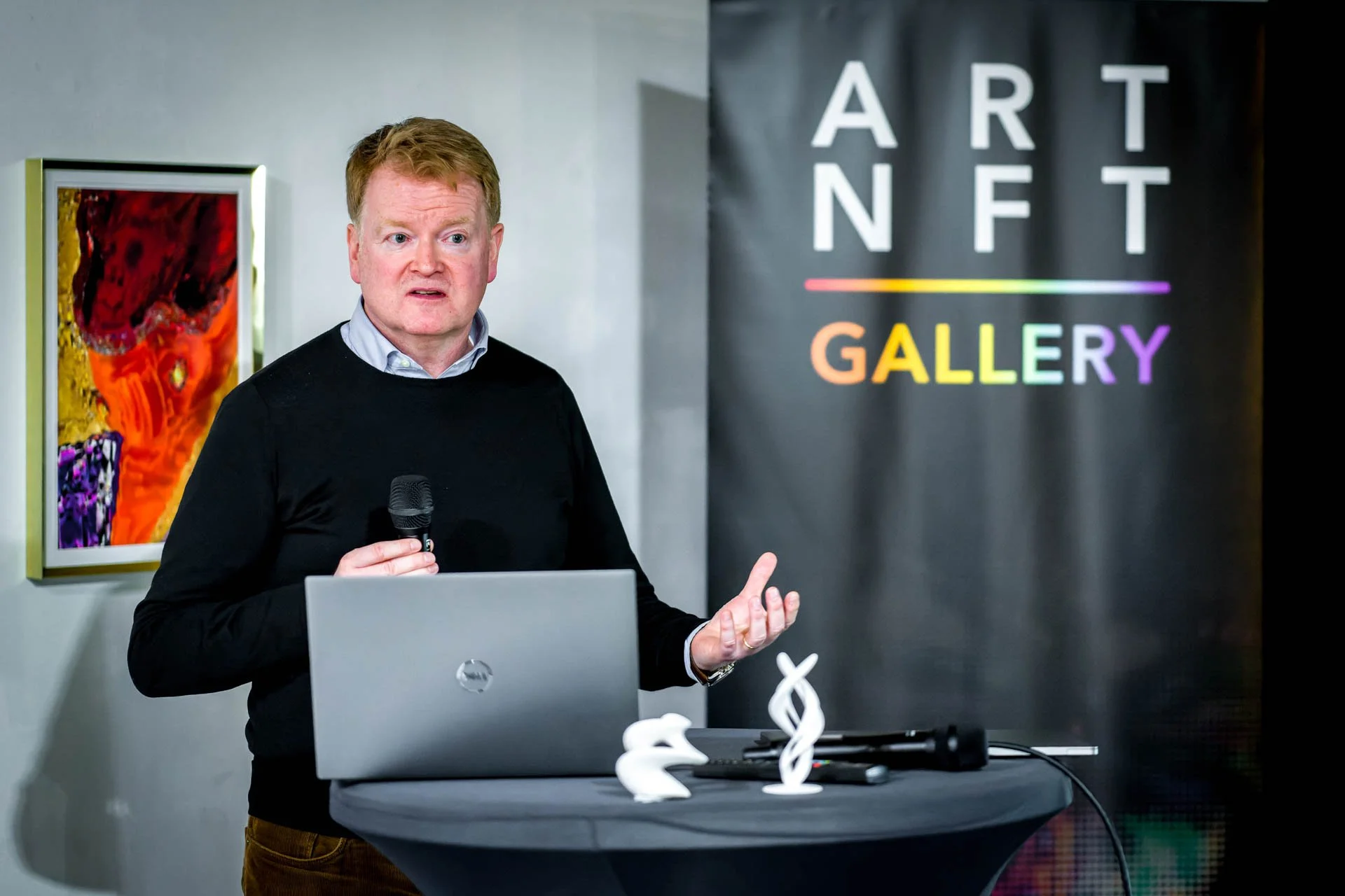 Tim Sinnaeve présente la stratégie de Barco, un microphone à la main, derrière un ordinateur portable à l’ART NFT Gallery.