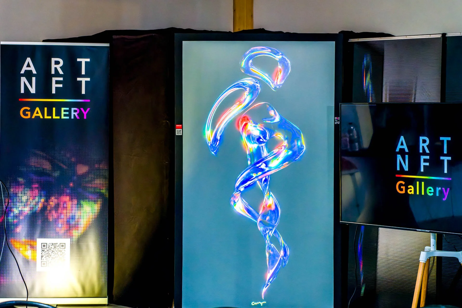 Exposition d'art numérique NFT avec des panneaux colorés et une œuvre lumineuse abstraite.